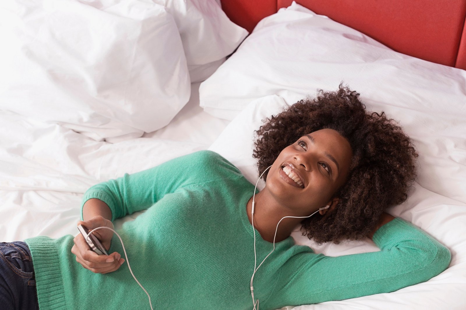 Woman listening to earphones on bed